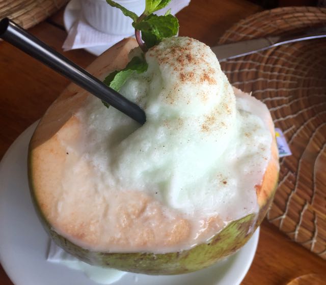 Abacaxi, água de coco e creme de menta batidos com gelo, servido no coco e polvilhado com canela.